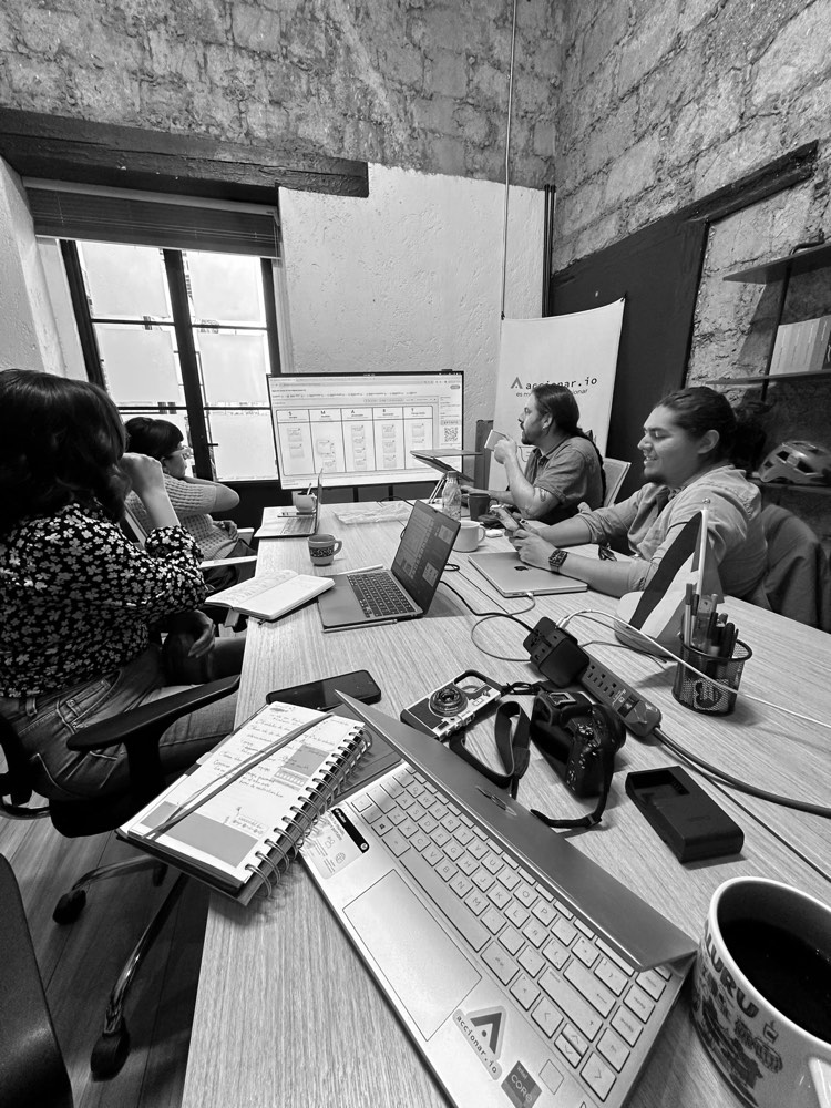 Equipo trabajando alrededor de una mesa con computadoras