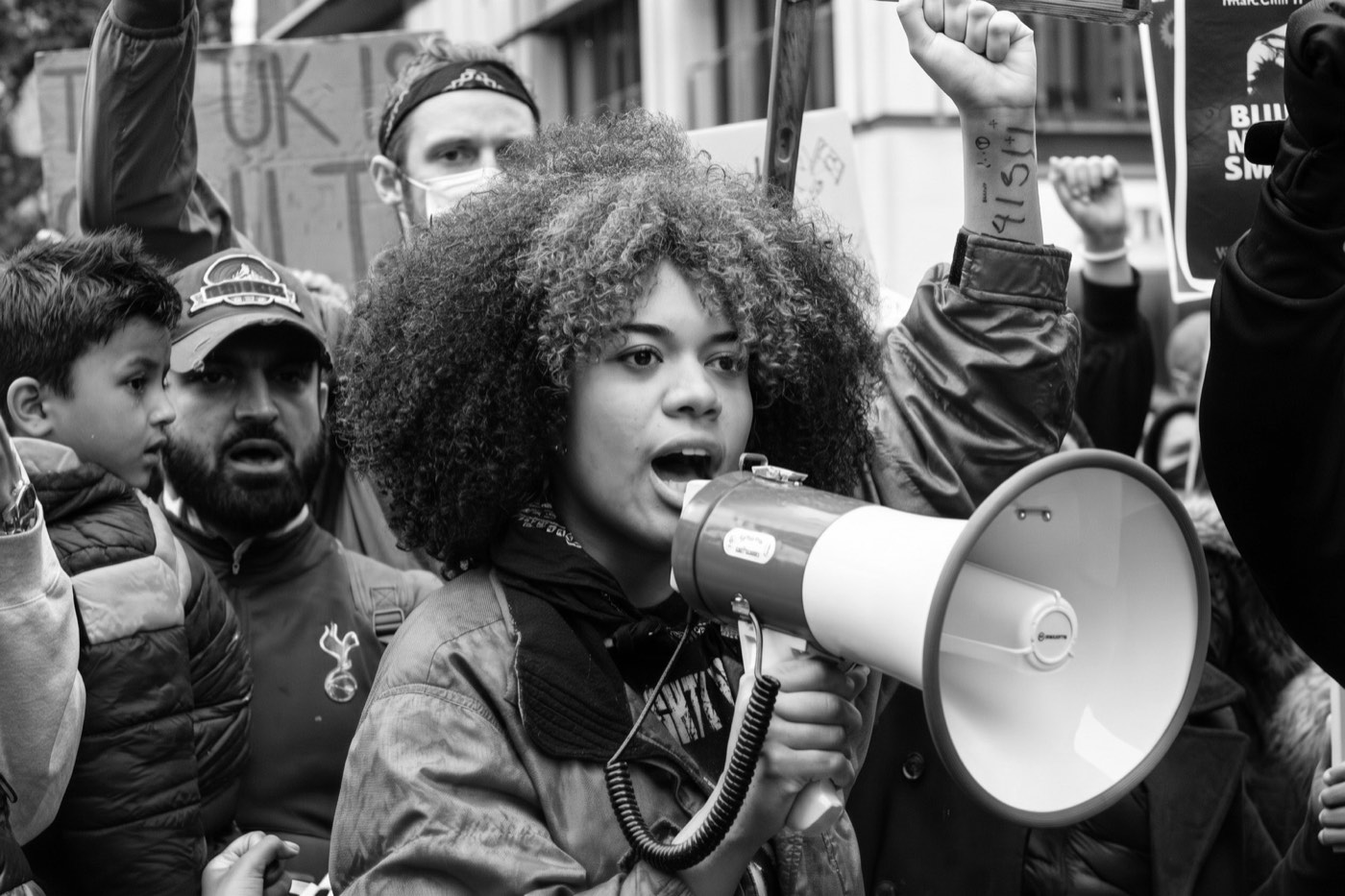 Una joven con un megáfono y el puño en alto al frente de una manifestación